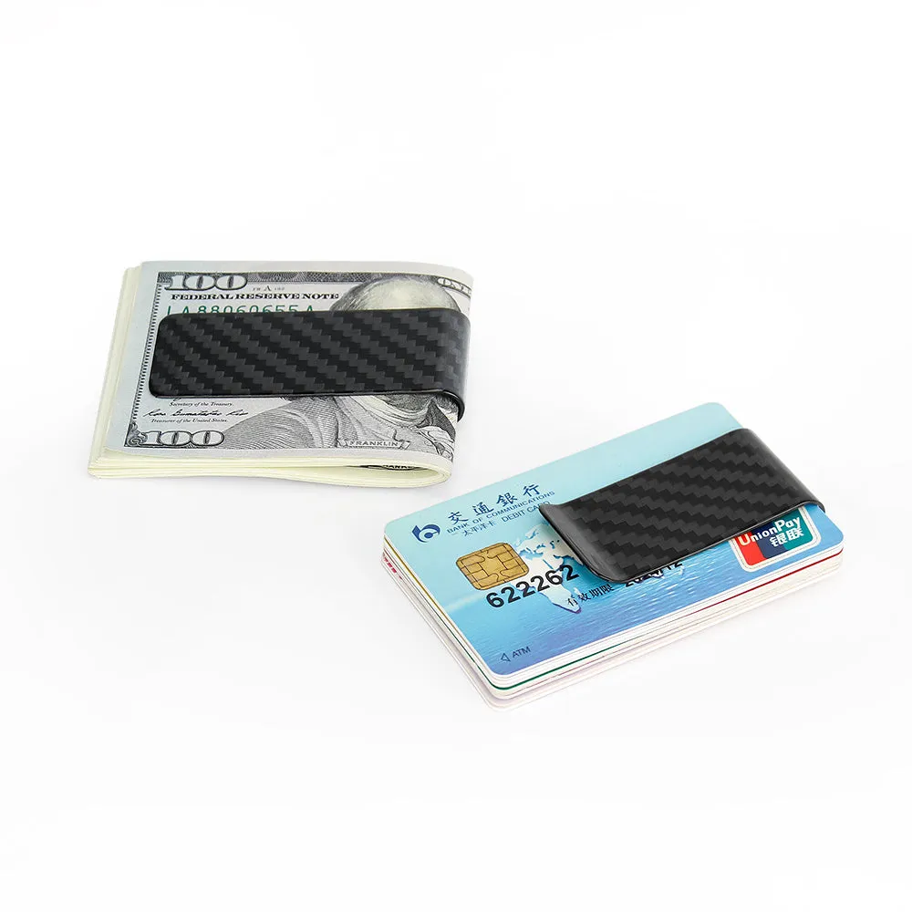 Glossy black genuine carbon fiber money clip on a flat surface, showing striped pattern and slim profile