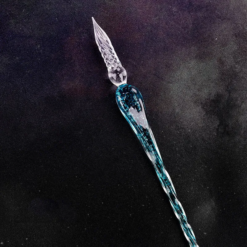 Crystal glass dip pen with transparent body and coloured ink, on a white background