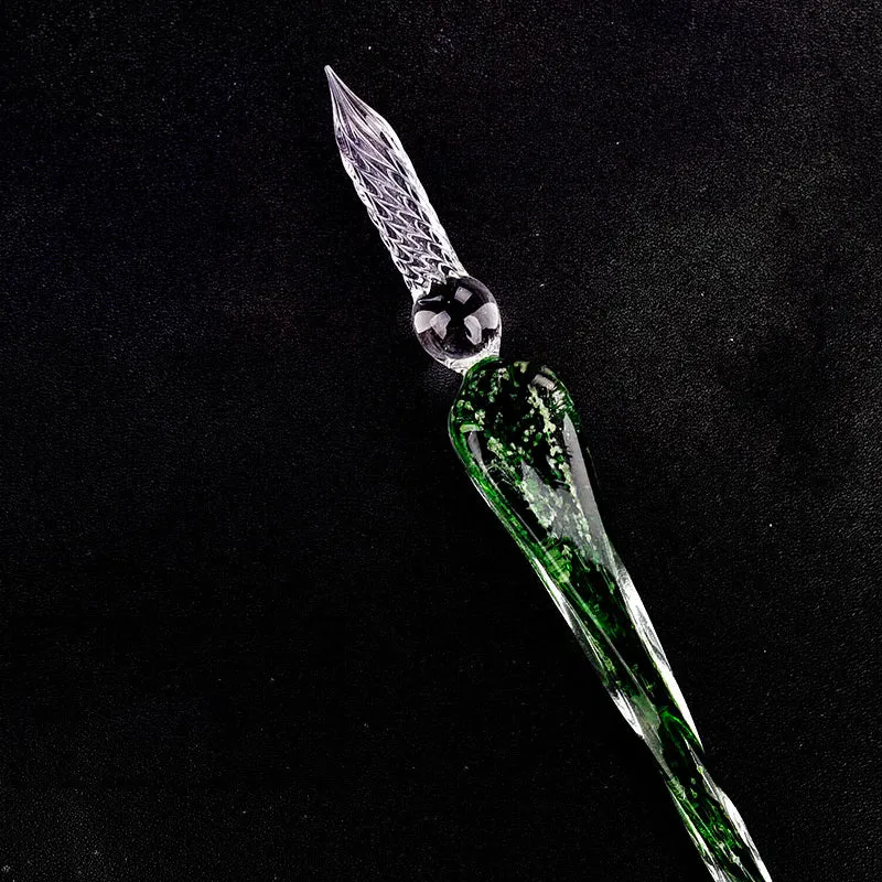Crystal glass dip pen with transparent body and coloured ink, on a white background