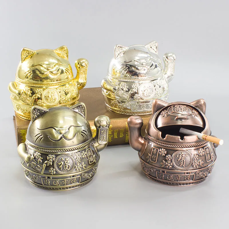 Zinc alloy Lucky Cat ashtray with cover in a gold-black finish on a table