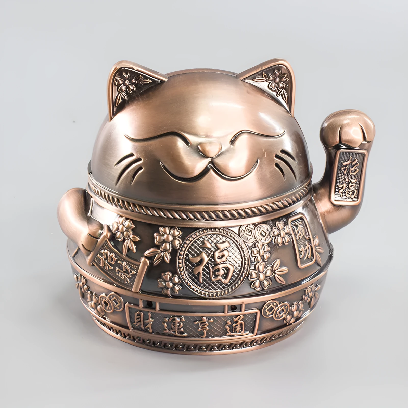 Zinc alloy Lucky Cat ashtray with cover in a gold-black finish on a table