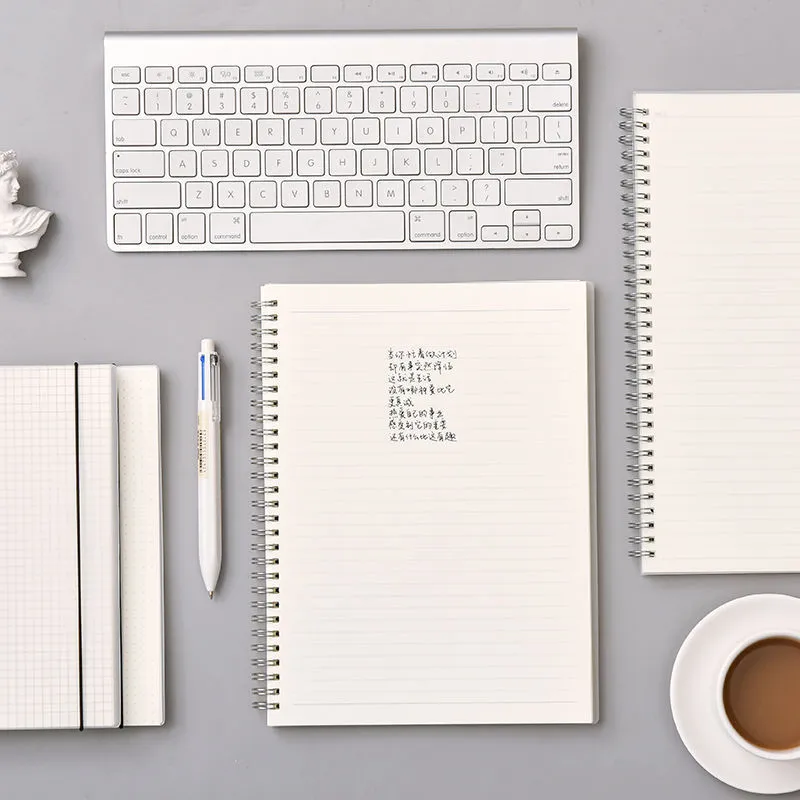 B5 coil grid notebook with Pp cover, open showing lined pages on a desk