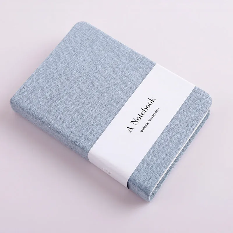 Cloth-covered wire-bound notebook with 132 pages, small size 10.5x14.5cm, showing blank and ruled pages in blue