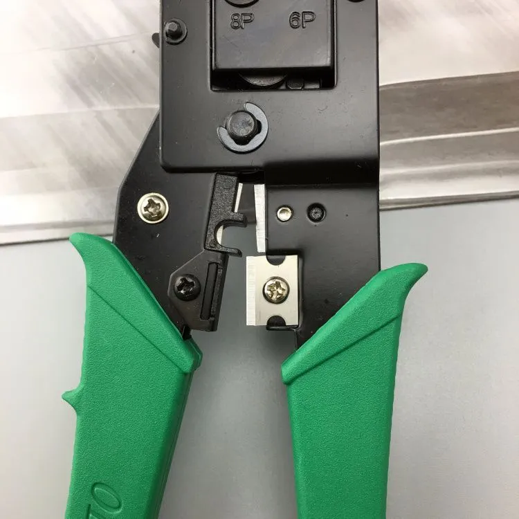 Green dual-purpose crystal head net pliers with tool steel jaws and plastic handle on plain background