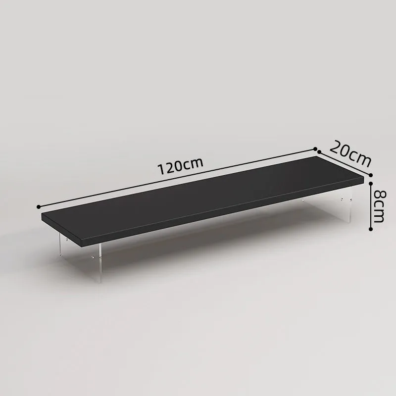Black computer riser with acrylic legs on desk under monitor