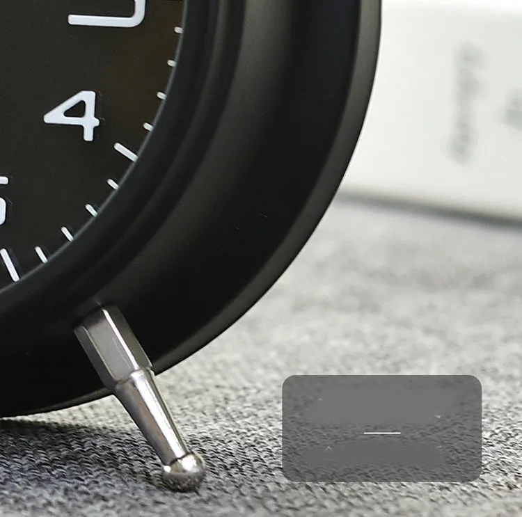 Large black metal alarm clock with luminous display and silent sweep movement on a bedside table