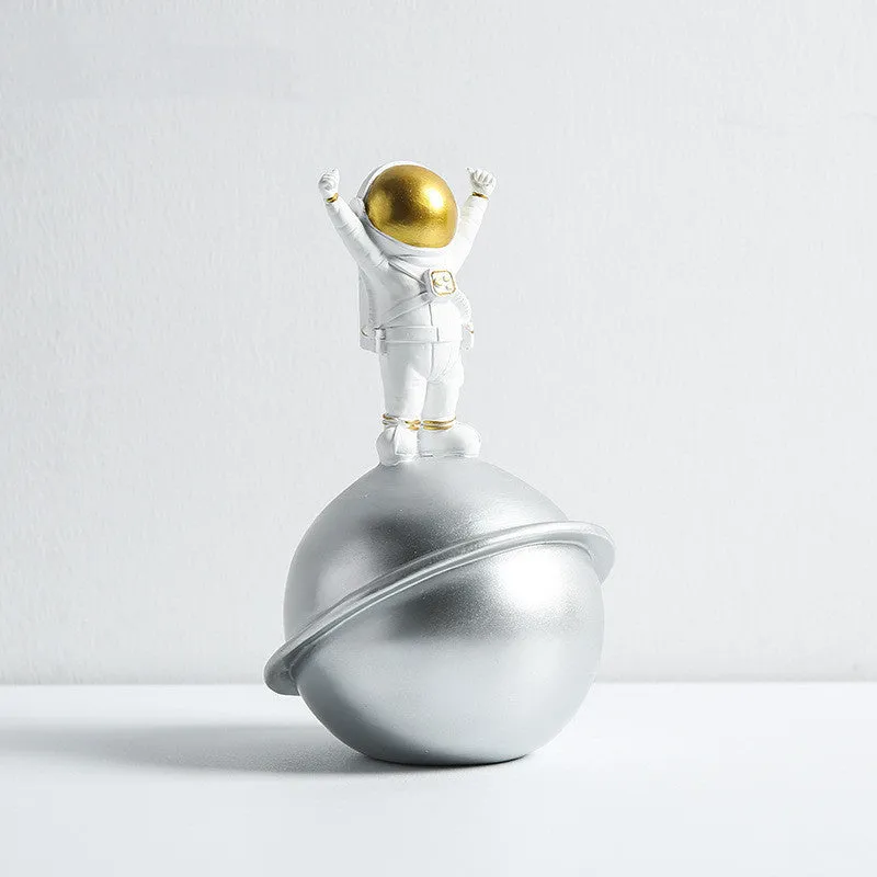 Astronaut resin clock trinket decoration in gold finish on a wooden desk with a bookshelf in background