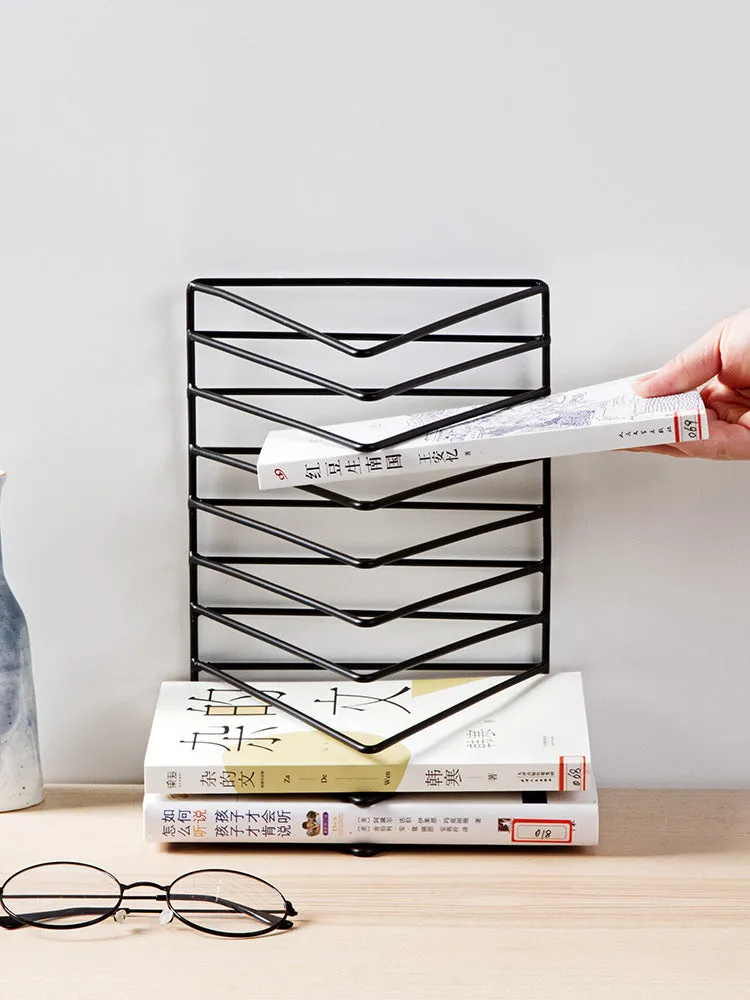 Wrought iron triangle book stand in black on a desk holding a book upright