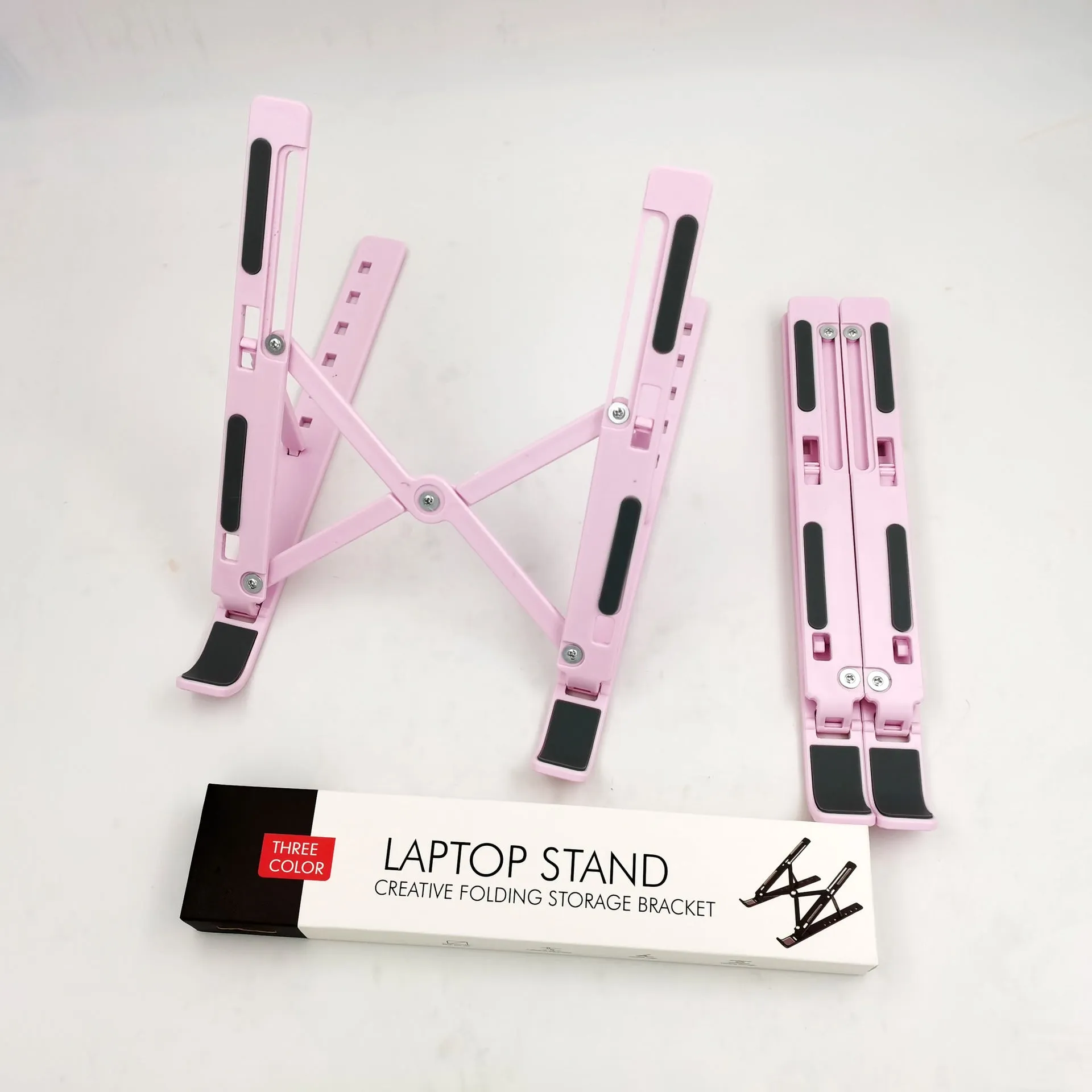 Folding aluminium alloy laptop stand in grey on a wooden desk, showing adjustable width and non-slip pads