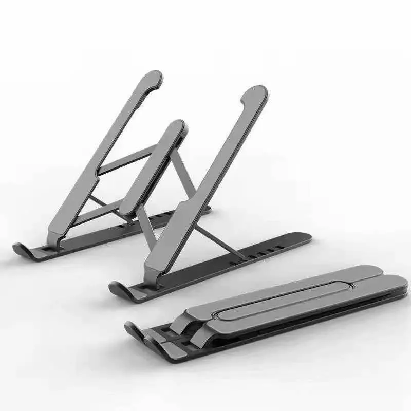 Folding aluminium alloy laptop stand in grey on a wooden desk, showing adjustable width and non-slip pads
