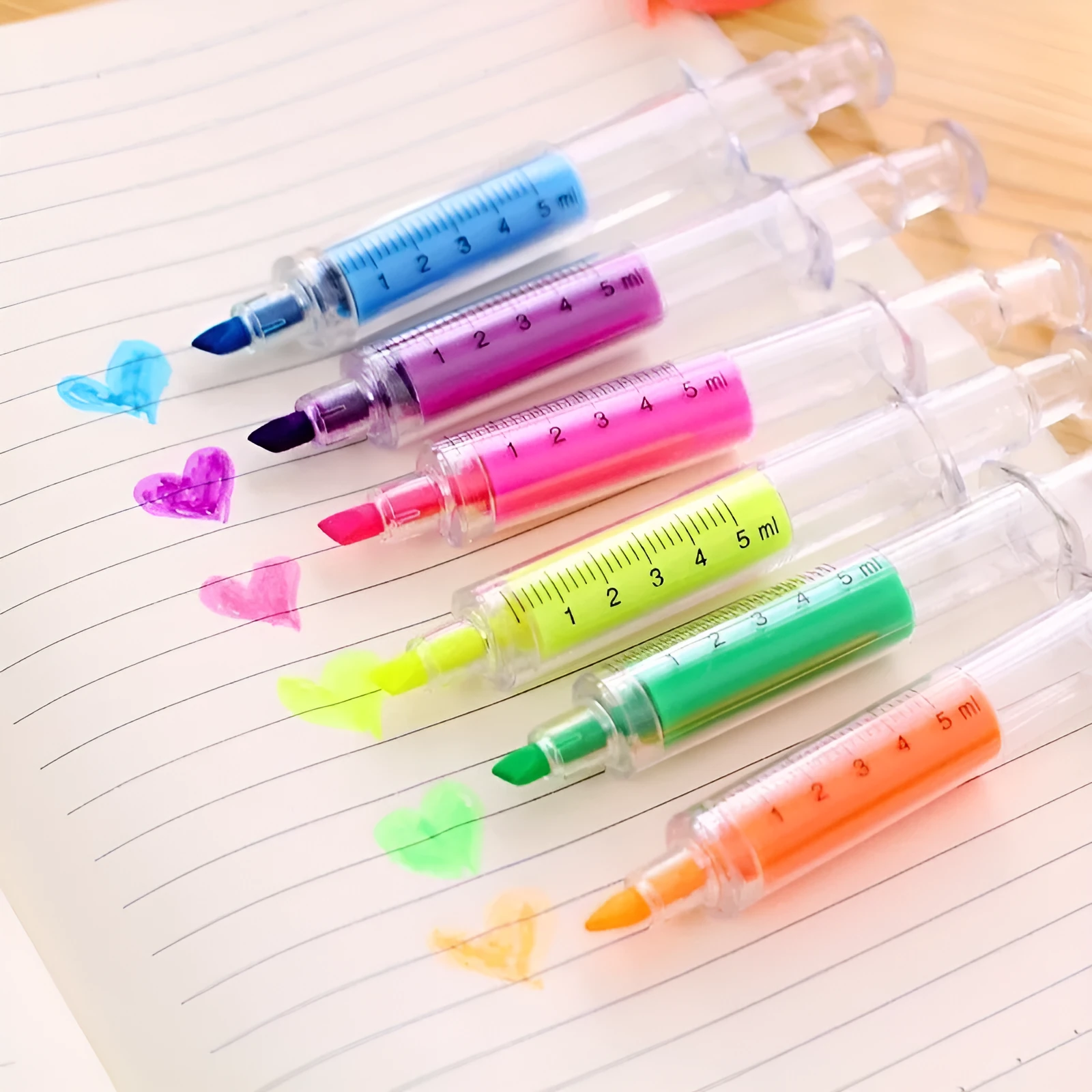 Six syringe-shaped fluorescent highlighter pens in assorted colours on a white background