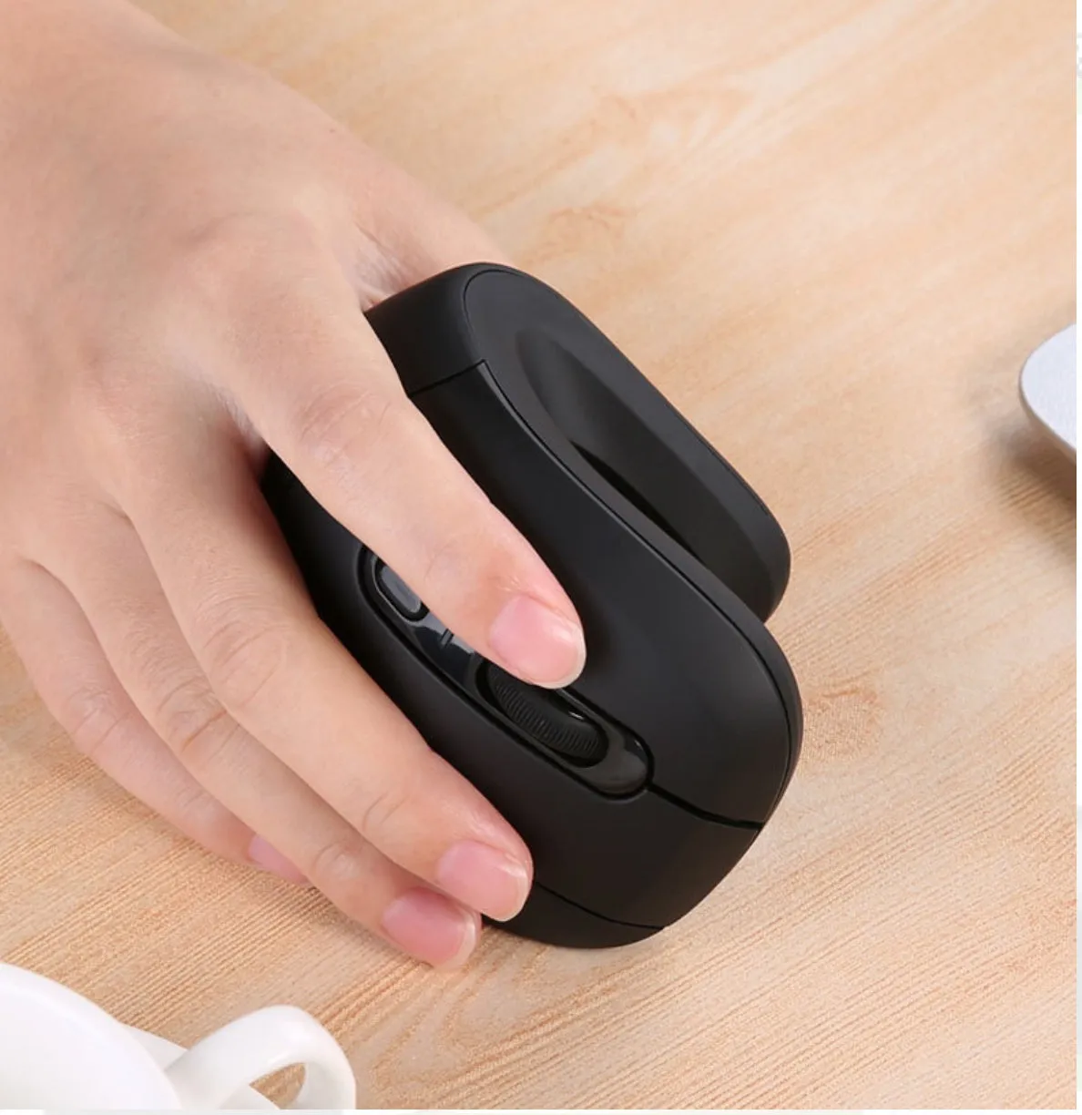 Wireless vertical mouse in black with ergonomic shape, six buttons, and diamond-pattern surface on a desk