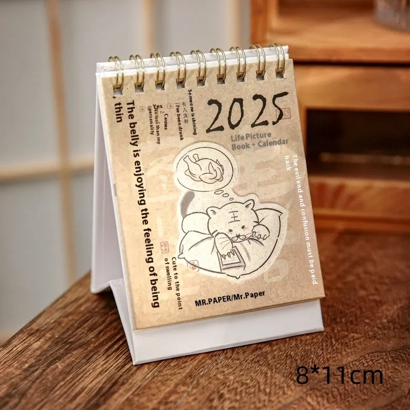Small 2025 mini desk calendar open to a daily page, showing modern simple design on a desk.