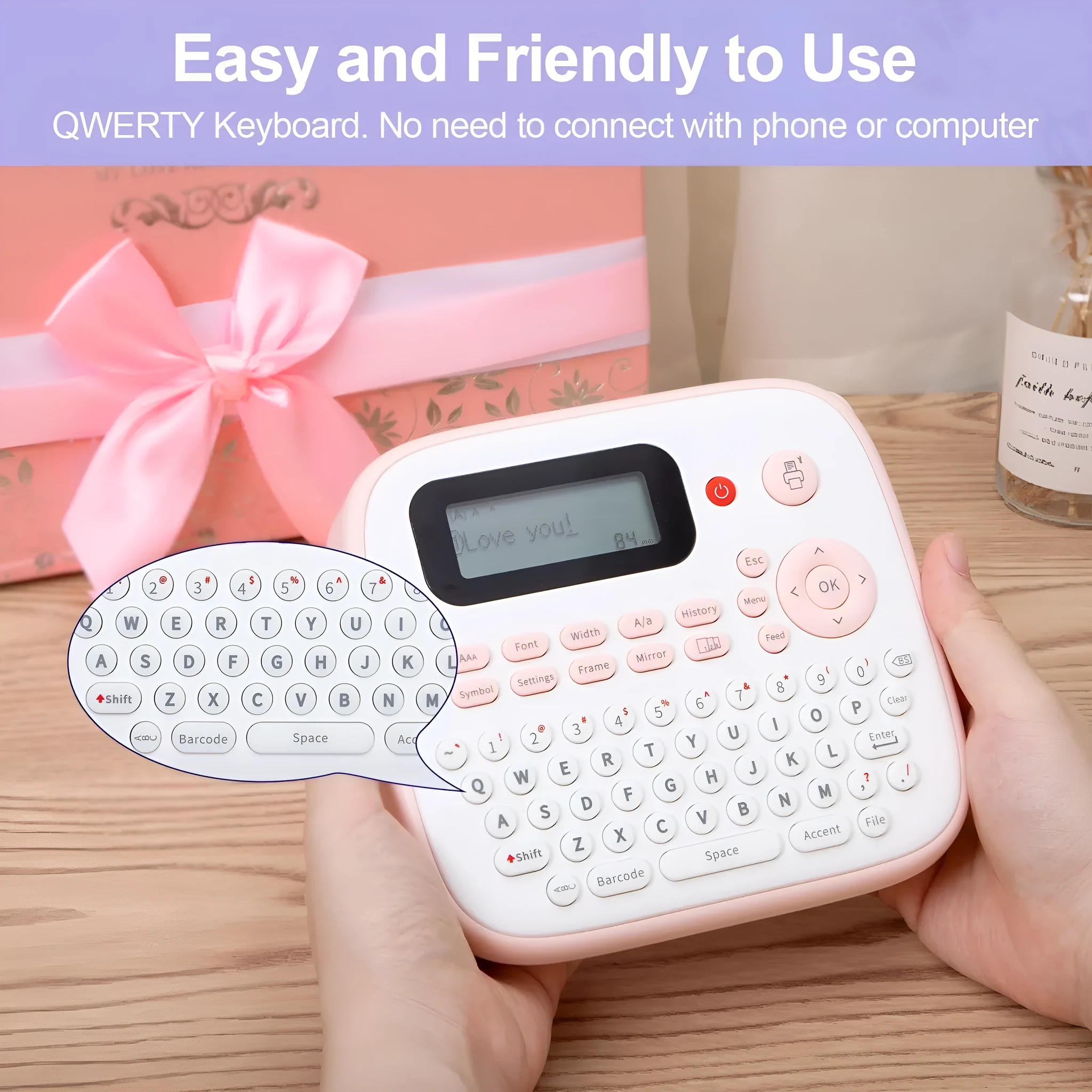 Mini portable ink-free Bluetooth label printer in pink with label tape roll, UK AC adapter, and user manual on a desk