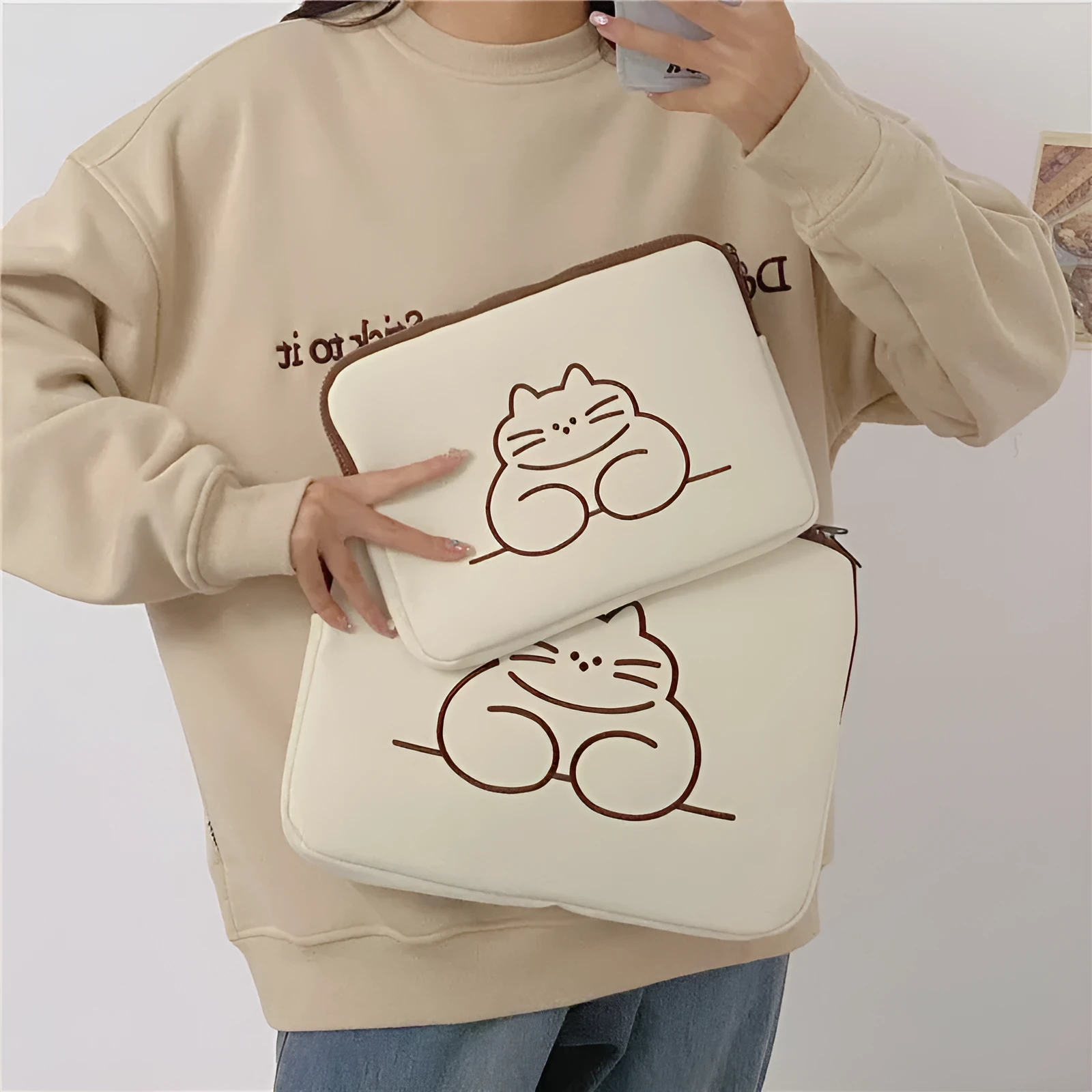 Nylon laptop sleeve with embroidered cat design and zipper closure, shown in small and large sizes.