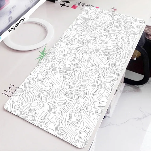 Large black and white gaming mouse pad with non-slip rubber bottom and cloth cover on a desk