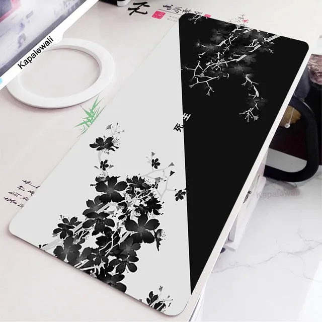 Large black and white gaming mouse pad with non-slip rubber bottom and cloth cover on a desk