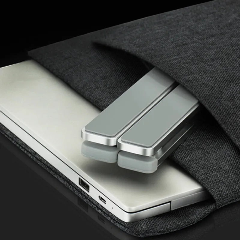 Folding laptop stand in silver with adjustable angle, holding a laptop, showing hollow bottom and non-slip silicone pads