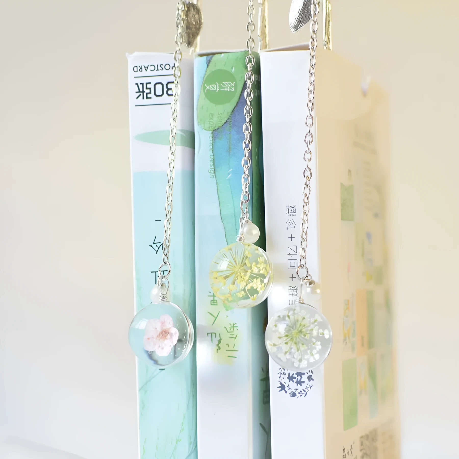 Creative metal bookmark with a dried flower inside, showing colour options like blue starry sky and dandelion.