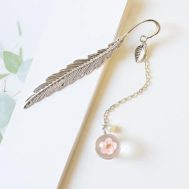 Creative metal bookmark with a dried flower inside, showing colour options like blue starry sky and dandelion.