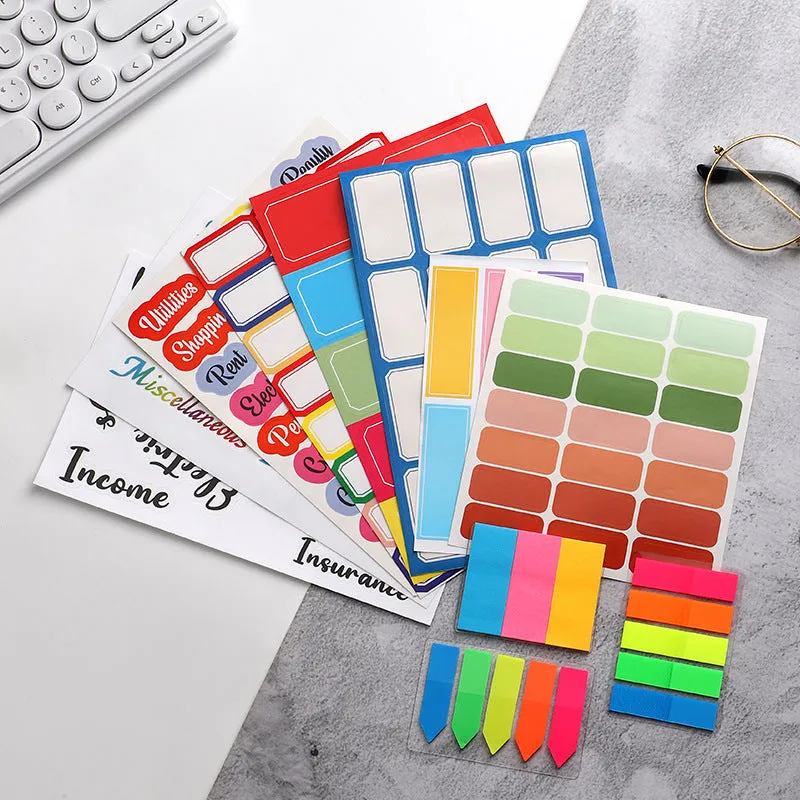 Assortment of handwritten labels, grid stickers, A6 rulers, and coloured sticky notes on a white background.