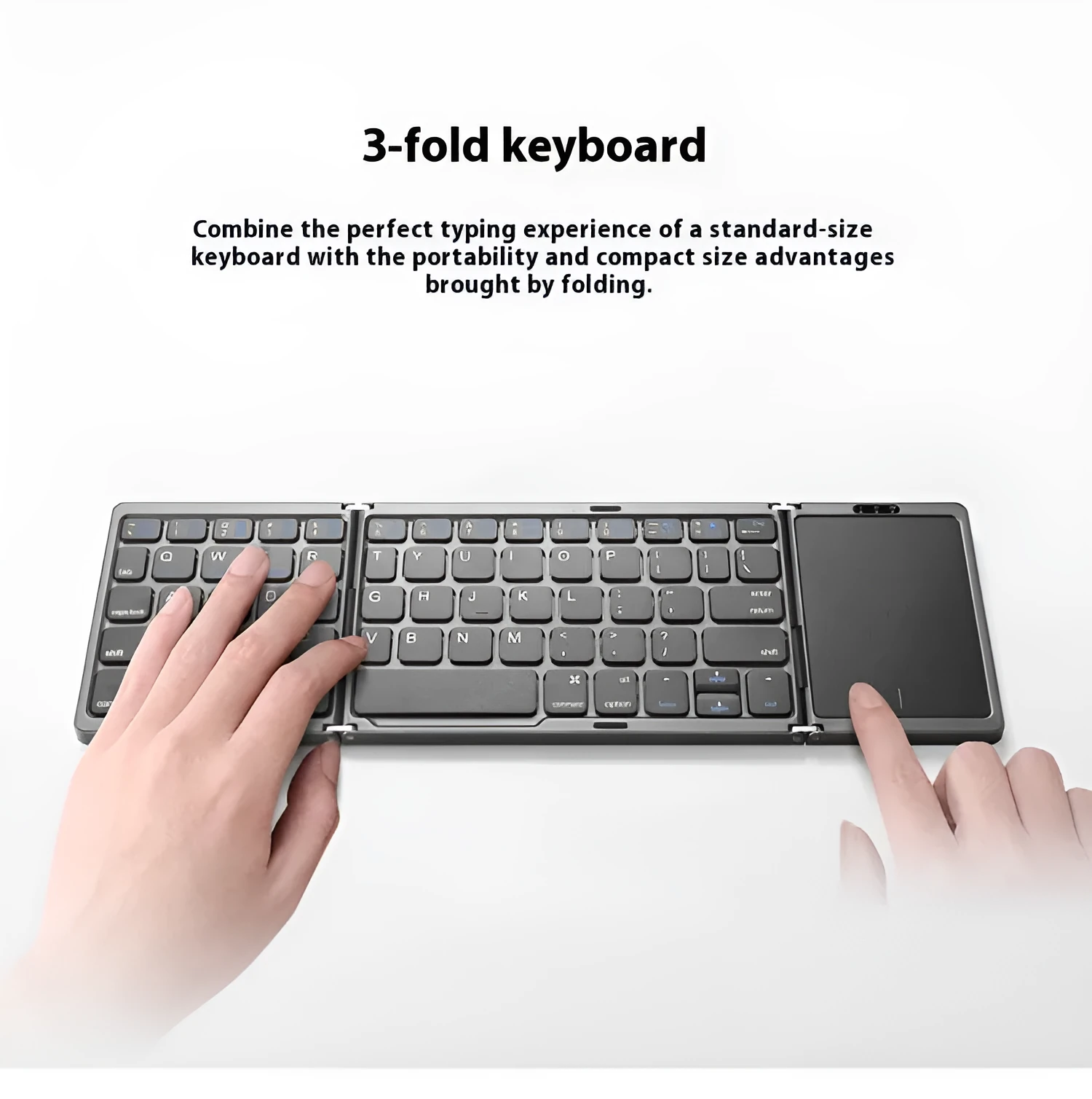 Three folding wireless Bluetooth keyboard with touch pad in black, open on a table next to a mobile phone