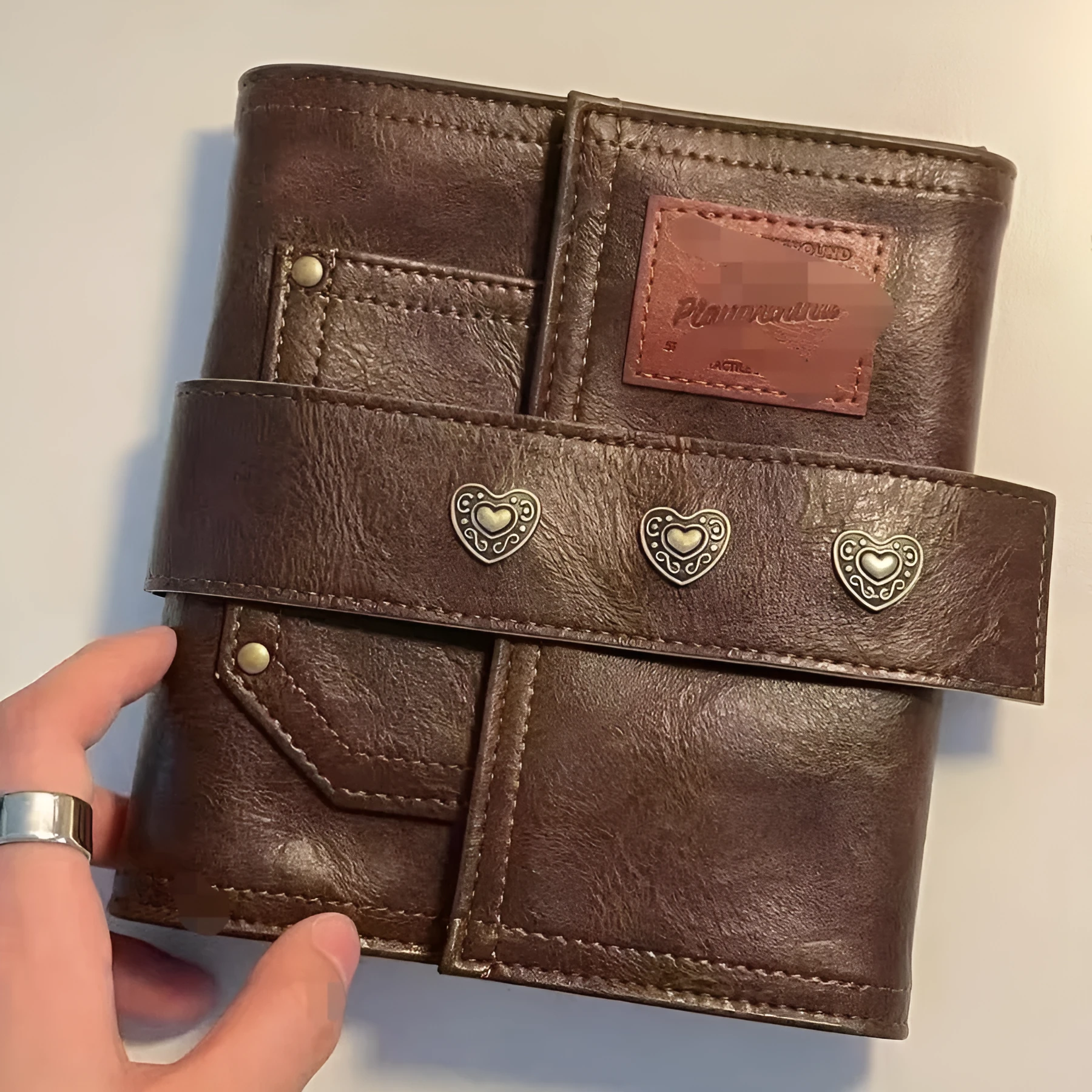 Brown retro-style A7 notebook with a PU leather-look cover and metal buckle closure, showing loose-leaf binding.