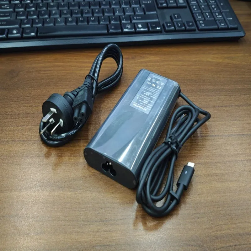 Black 65W USB-C laptop power adapter with multiple international plug attachments on white background