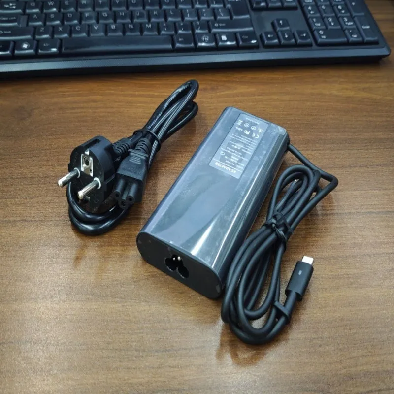 Black 65W USB-C laptop power adapter with multiple international plug attachments on white background
