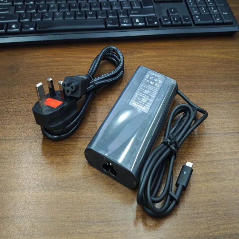 Black 65W USB-C laptop power adapter with multiple international plug attachments on white background