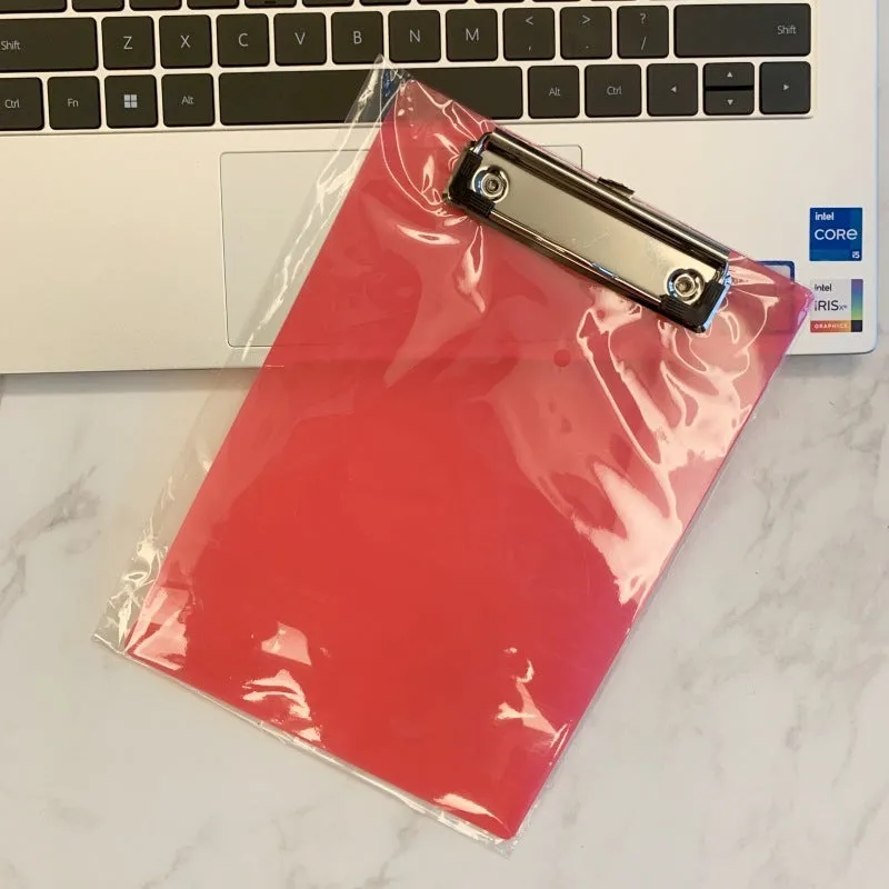 Clear A4 plate holder with metal clip and transparent writing pad in blue colour on a desk.