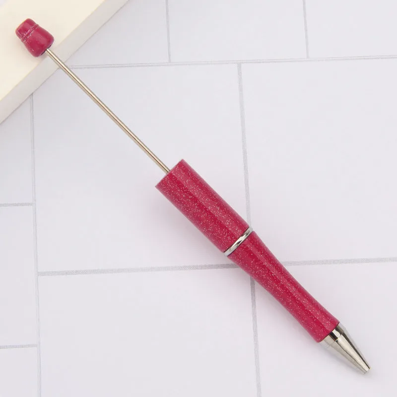 Colourful spinning ballpoint pen with plastic beads on a white background.