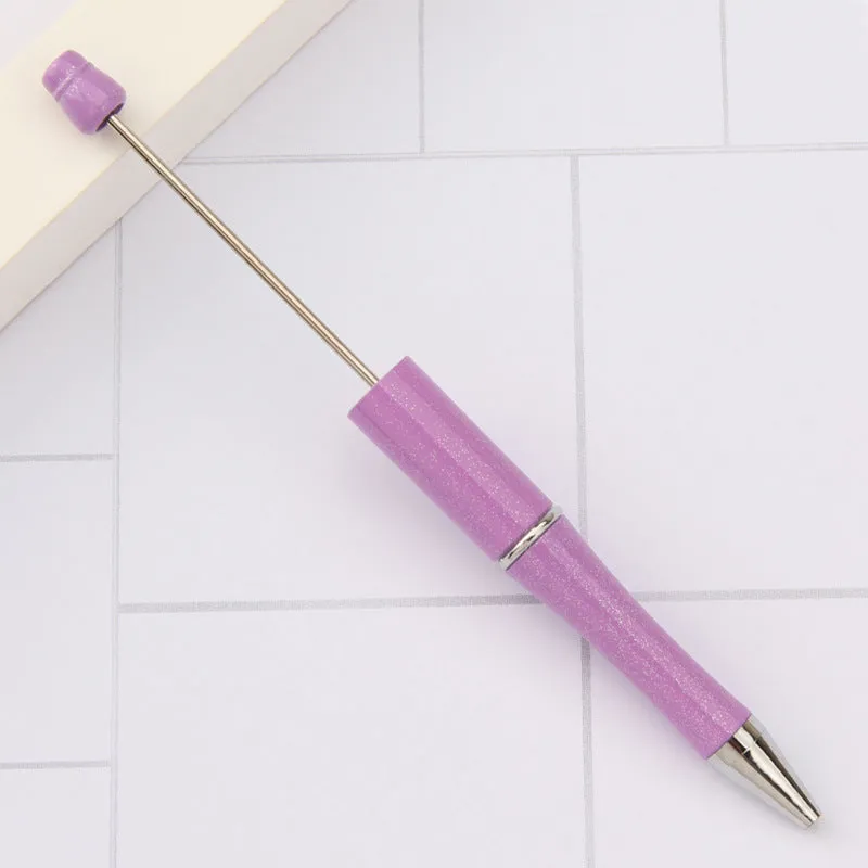 Colourful spinning ballpoint pen with plastic beads on a white background.