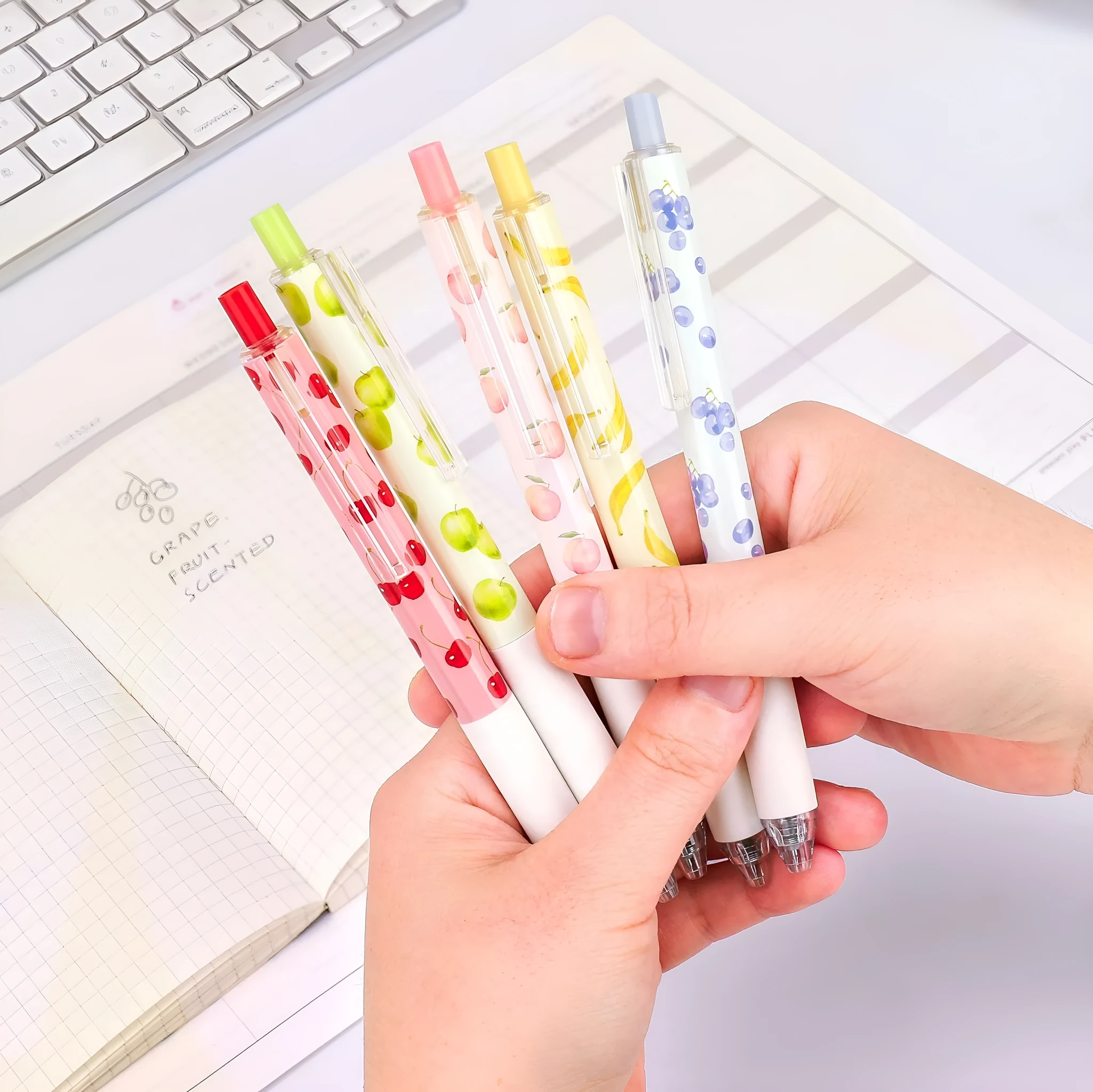 Three fruit scented press-action pens with 0.5mm quick-drying black refills on white background