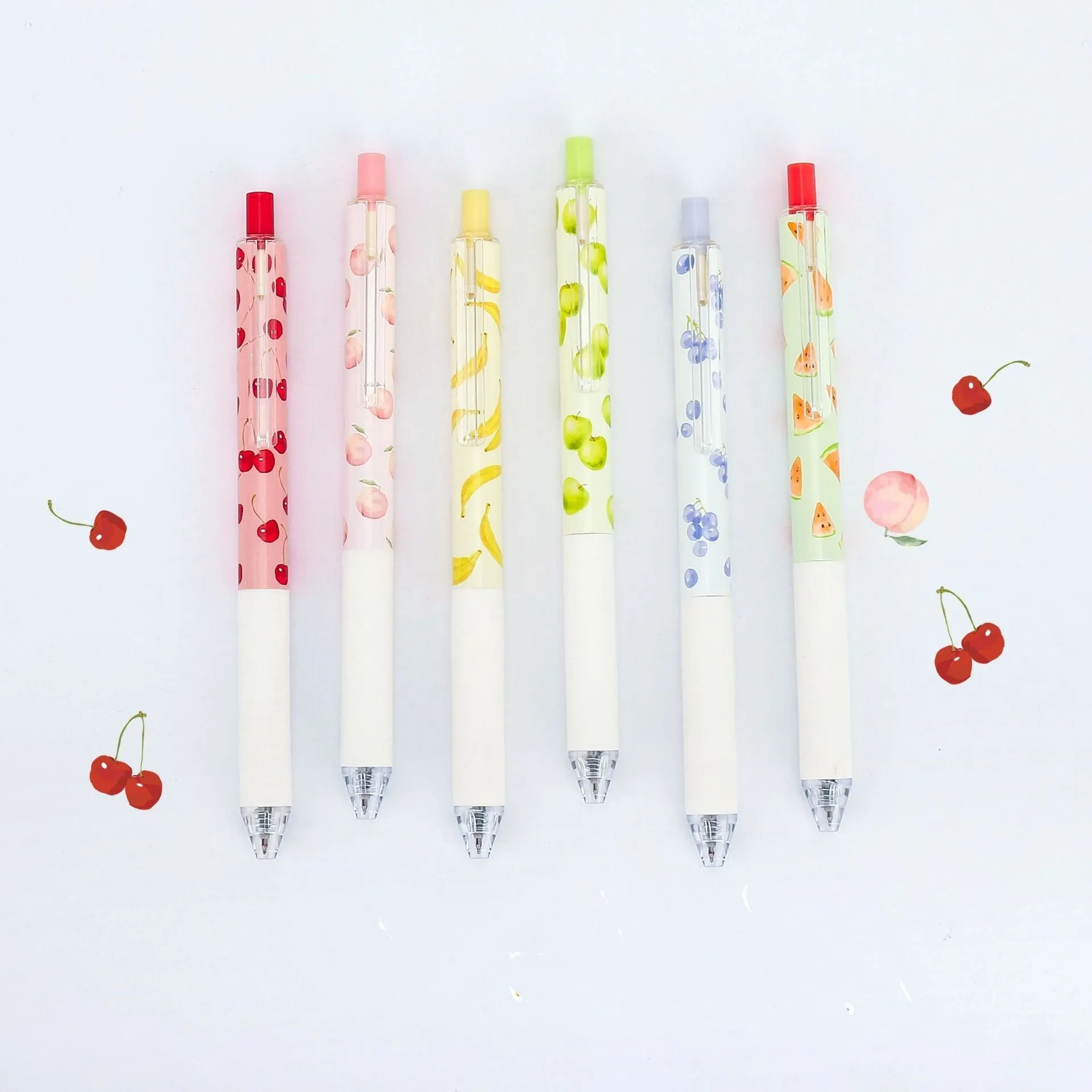 Three fruit scented press-action pens with 0.5mm quick-drying black refills on white background