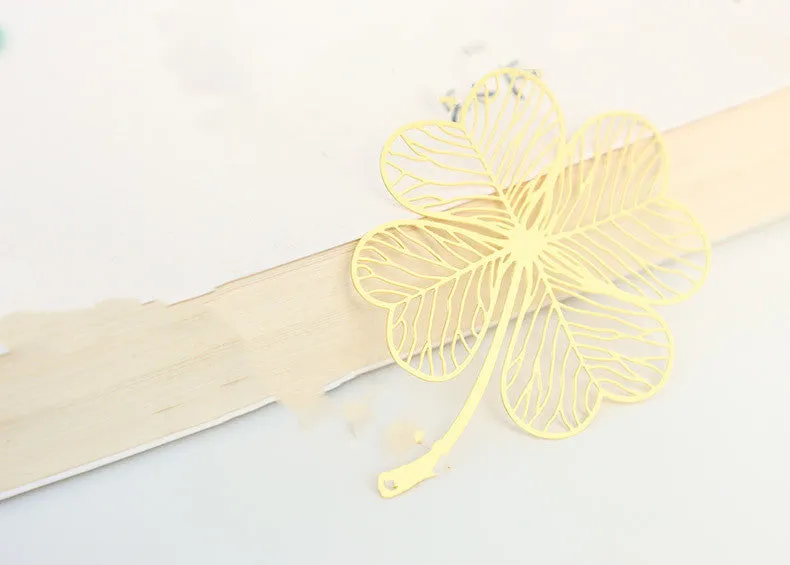 Detailed brass bookmark with hollow maple leaf pendant and rose gold tassel on a book page.