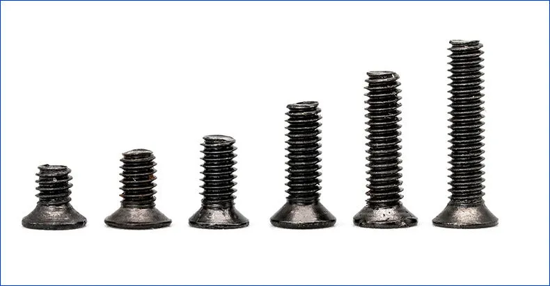 Black flat head M1.4 x 16mm laptop screws spilt from a box, showing cross slot drive and countersunk head profile.