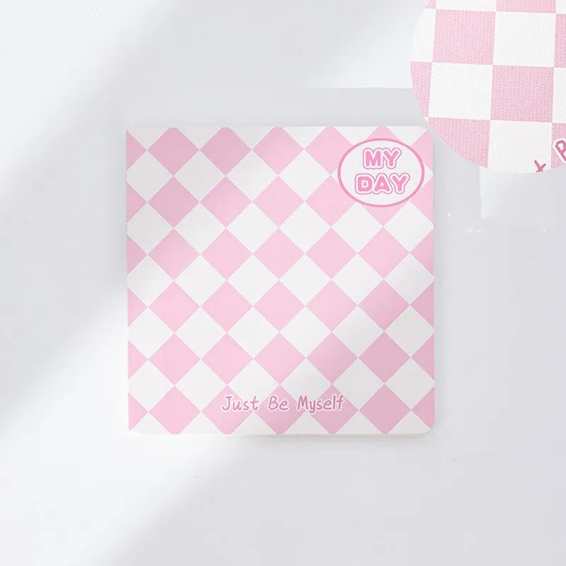 Ins style A5 grid notebook open on a desk, showing grid paper and one of twelve colourful cover designs like pineapple or checkerboard.