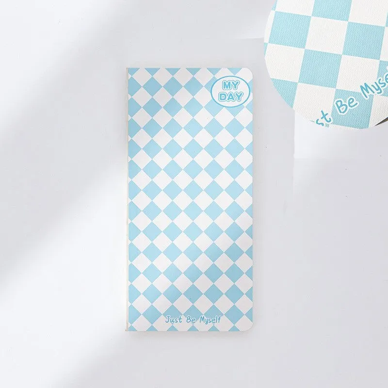 Ins style A5 grid notebook open on a desk, showing grid paper and one of twelve colourful cover designs like pineapple or checkerboard.