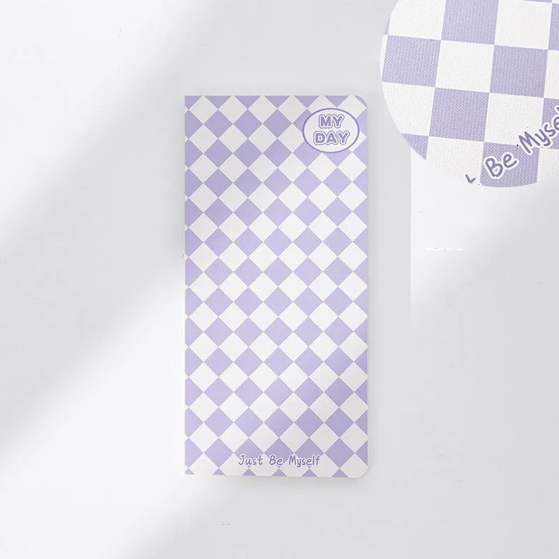 Ins style A5 grid notebook open on a desk, showing grid paper and one of twelve colourful cover designs like pineapple or checkerboard.